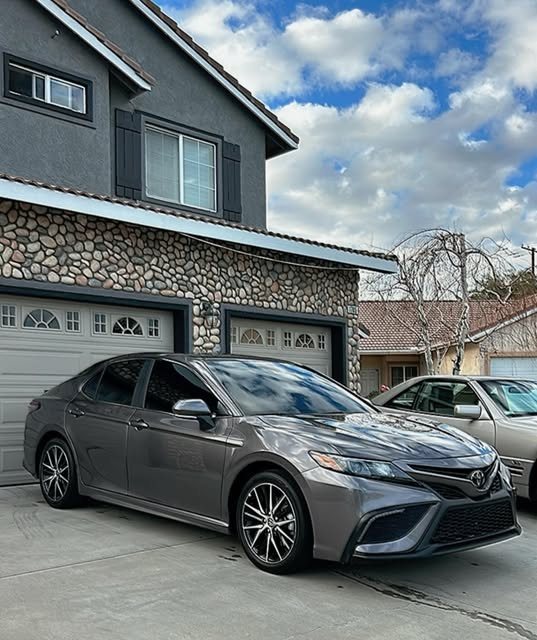 Grey Toyota Camry detailed in front of a stone garage